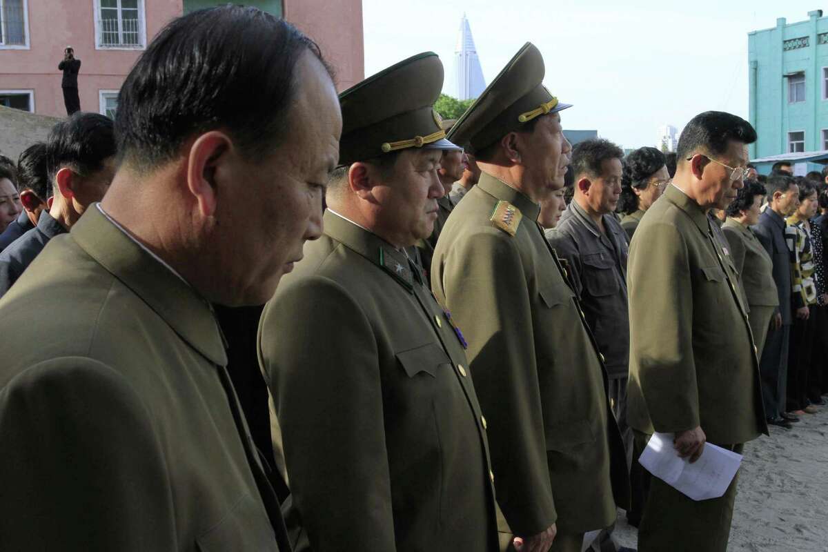 In this Saturday, May 17, 2014 photo, North Korean officials stand among the families of victims of an accident at an apartment construction site in Pyongyang, North Korea, during a gathering in the capital where senior officials apologized and took responsibility. The word of the collapse in the secretive nation's capital was reported Sunday morning by the North's official Korean Central News Agency, which gave no death toll but said that the accident was "serious" and upset North Korea's leader, Kim Jong Un. (AP Photo/Kim Kwang Hyon)