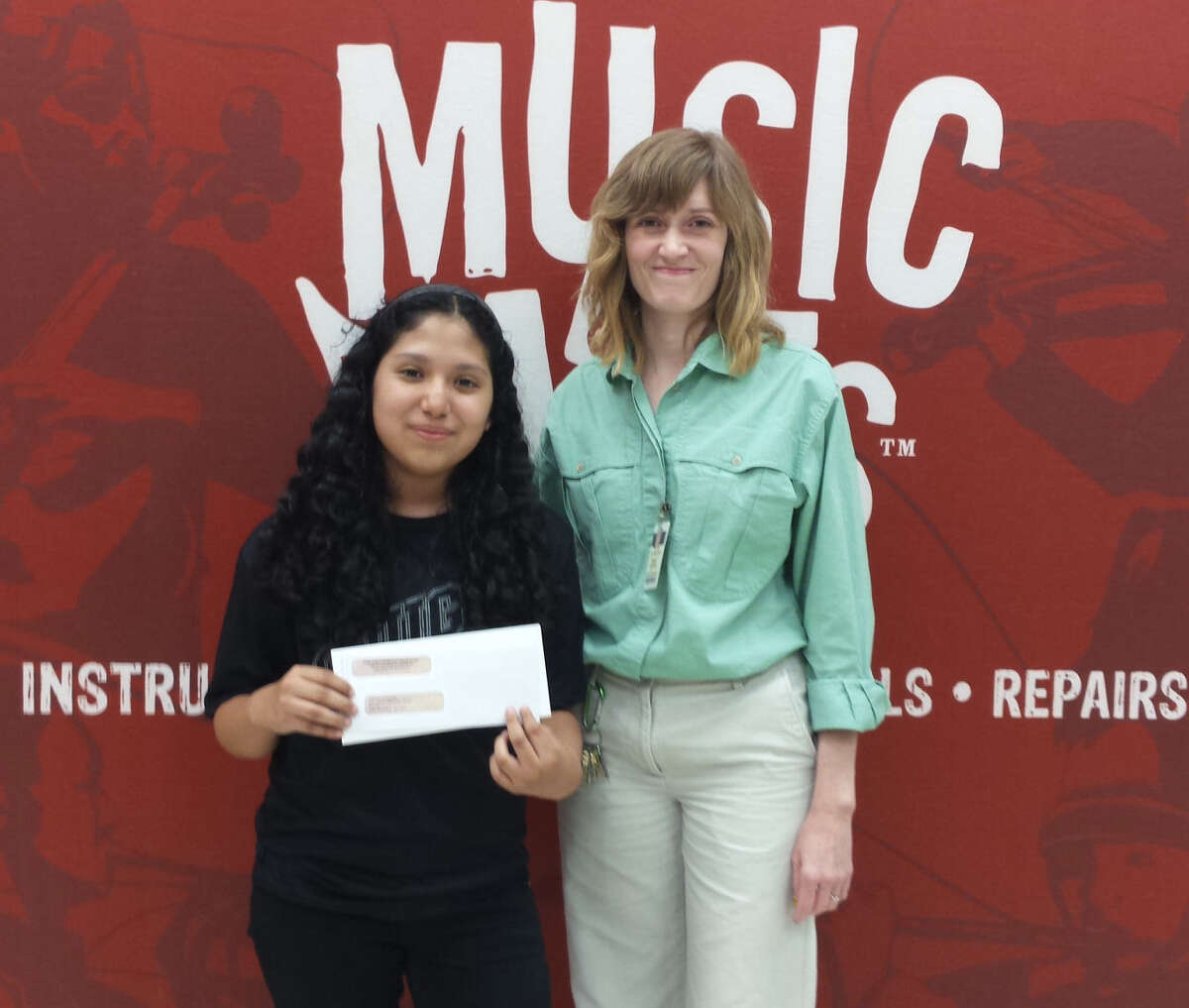 Sienna Cavazos, eighth-grade violinist at Anson Jone Middles School, poses with Sonja Alcorta, the school's music director. The young musician recently won a $1,000 scholarship for college from Music & Arts and SBO magazine for her essay on why music education is important to her.
