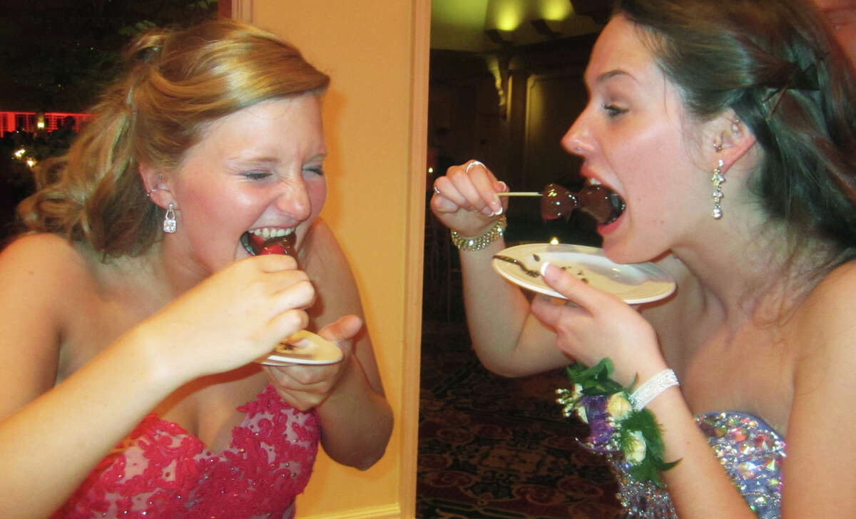Nina Barrett, left, and Emma Riggs show no mercy to their chocolate-covere strawberries during "Casino Royale," New Milford High School's Senior Prom at the Waterview in Monroe, May 17, 2014.