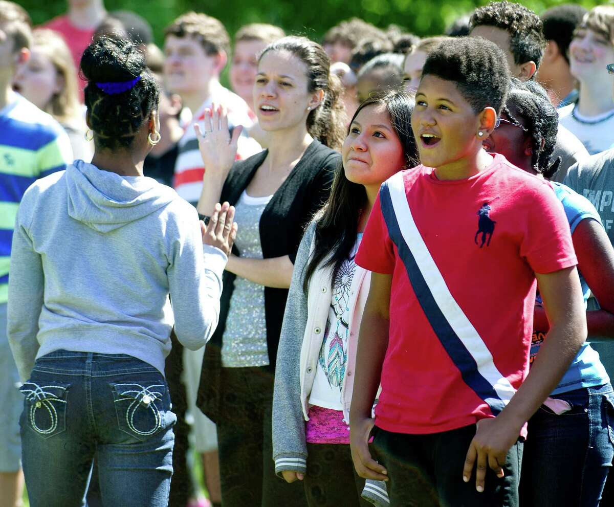 Math teacher Stephanie Valvano, left, gives out a high-five as Lina Cabrera, center, and John Santos, right, look up at firefighters in a bucket during Dolan Middle School's "Lunar Egg Drop" exercise, which was designed to teach students about the challenges of dropping a rover on another planet, on Tuesday, May 20, 2014.