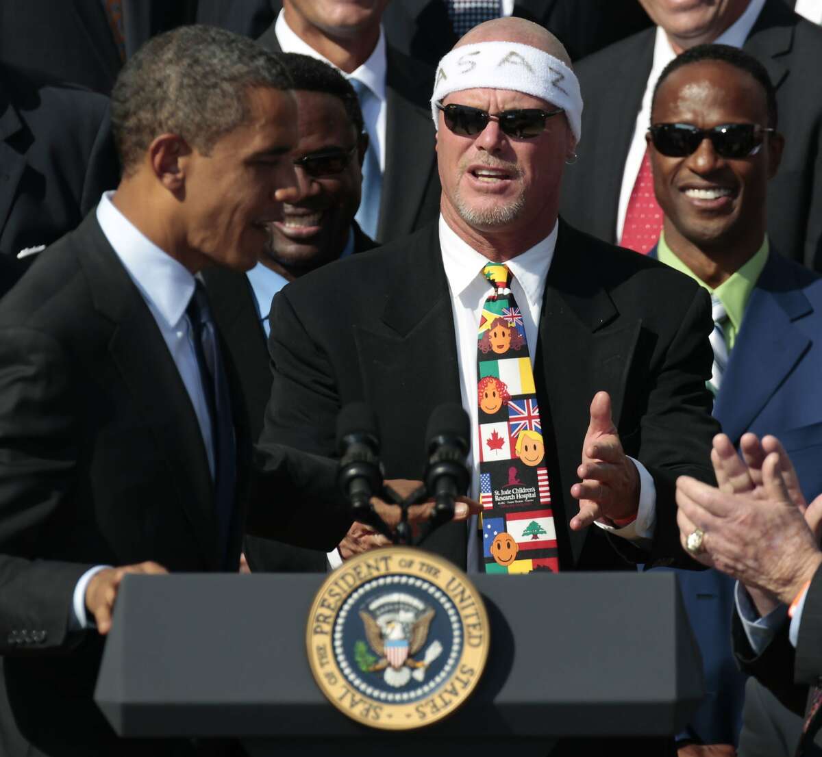 FILE - In this Oct. 7, 2011 file photo, President Barack Obama, left, looks towards quarterback Jim McMahon, wearing headband, as he honors the 1985 Super Bowl XX Champion Chicago Bears football team during a ceremony on the South Lawn of the White House in Washington. A group of retired NFL players says in a lawsuit that the league illegally supplied them with risky painkillers that numbed their injuries and led to medical complications. Attorney Steven Silverman says his firm filed the lawsuit Tuesday, May 20, 2014, in federal court in San Francisco. The eight named plaintiffs include Hall of Fame defensive end Richard Dent and quarterback Jim McMahon. (AP Photo/Pablo Martinez Monsivais, File)