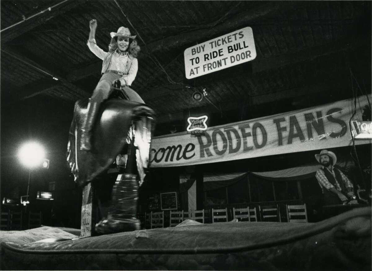05/21/1980 - Lynn Wyatt, one of the chairmen of the benefit premiere of Urban Cowboy, rides the mechanical bull at Gilley's Club.