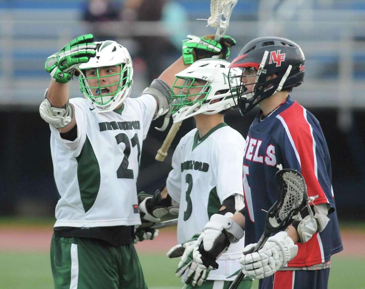 New Milford's Alex MacDonald (21) and Stephen Berry (3) celebrate a goal as New Fairfield's James Lewis looks on in New Milford's 13-7 win over New Fairfield in the high school boys lacrosse game at Brookfield High School in Brookfield, Conn. Friday, May 23, 2014.