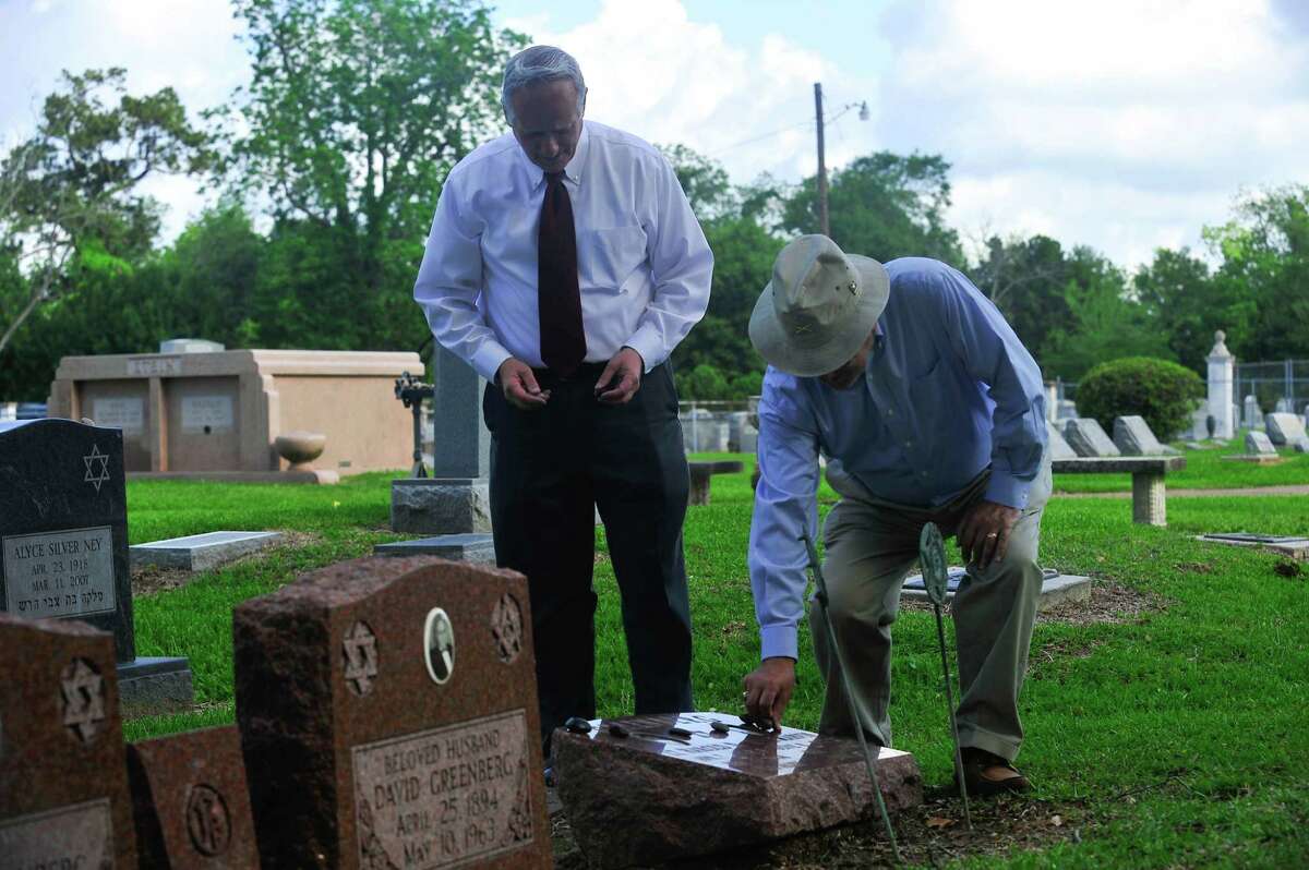 Alan Sampson, left, and Ralph Night place stones on the graves of the Greenberg brothers in Hebrew Rest Cemetery on Tuesday. Photo provided by Jon Shapley