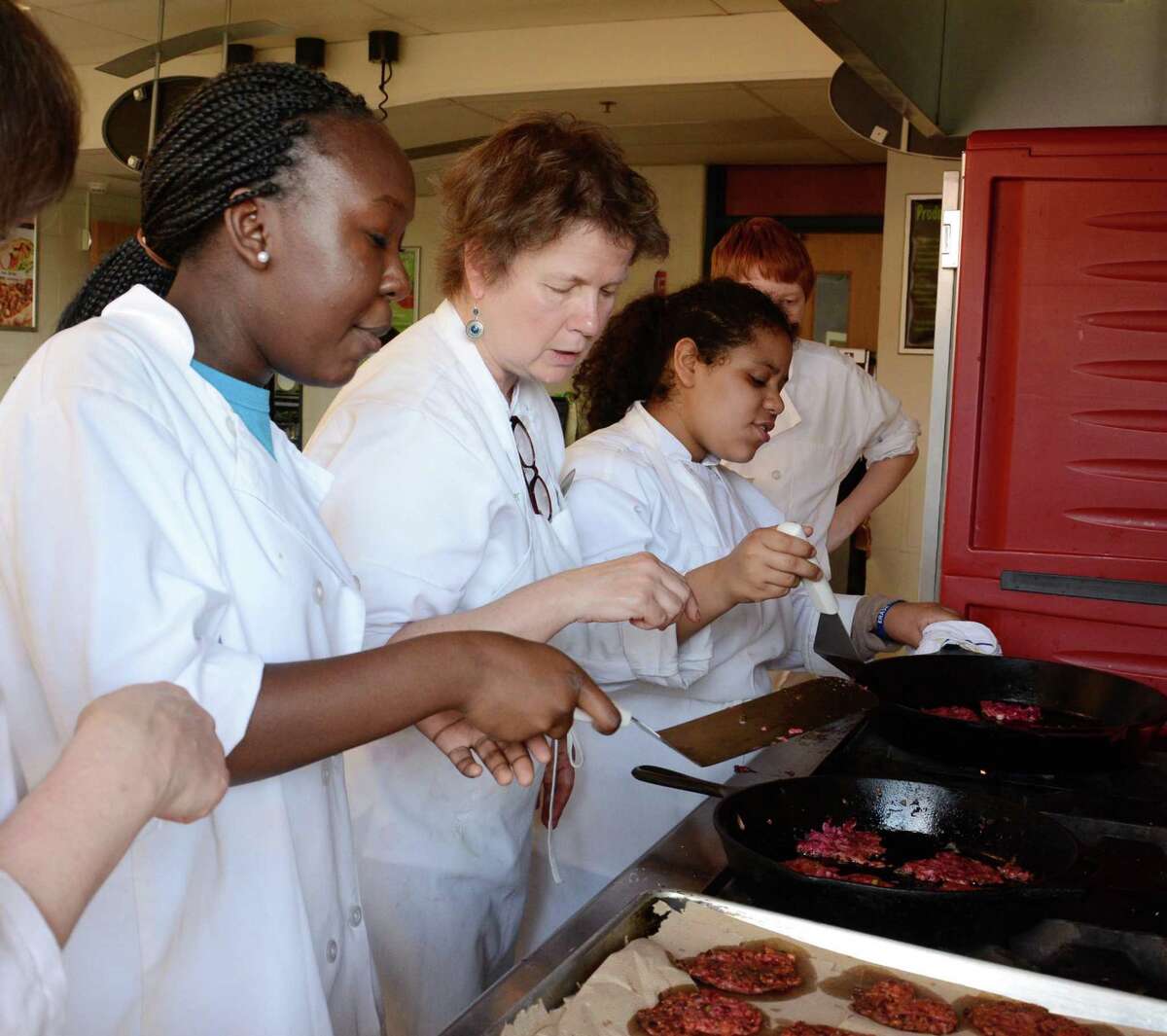 Plow-To-Plate Chef Anne Gallagher, center, shows students Sydney Knight, 15, left and Crystal Rivas, 15, right, how to saute roasted beet and celeriace latkes during an after school Chef Advocacy program on Tuesday, May 27, 2014.