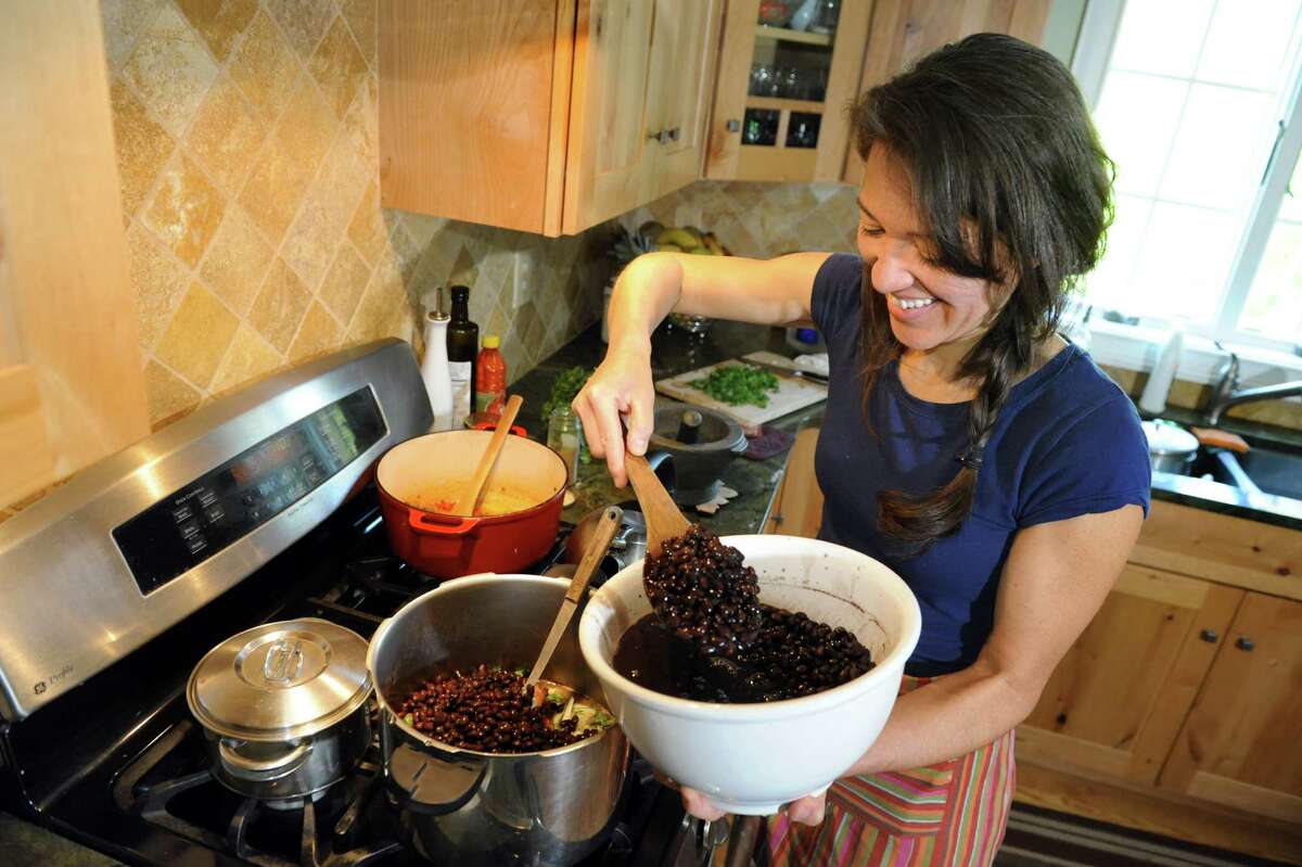 Ellie Markovitch, a native of Brazil, adds black beans to a national dish at her home on Wednesday, May 21, 2014, in Brunswick, N.Y. (Cindy Schultz / Times Union)