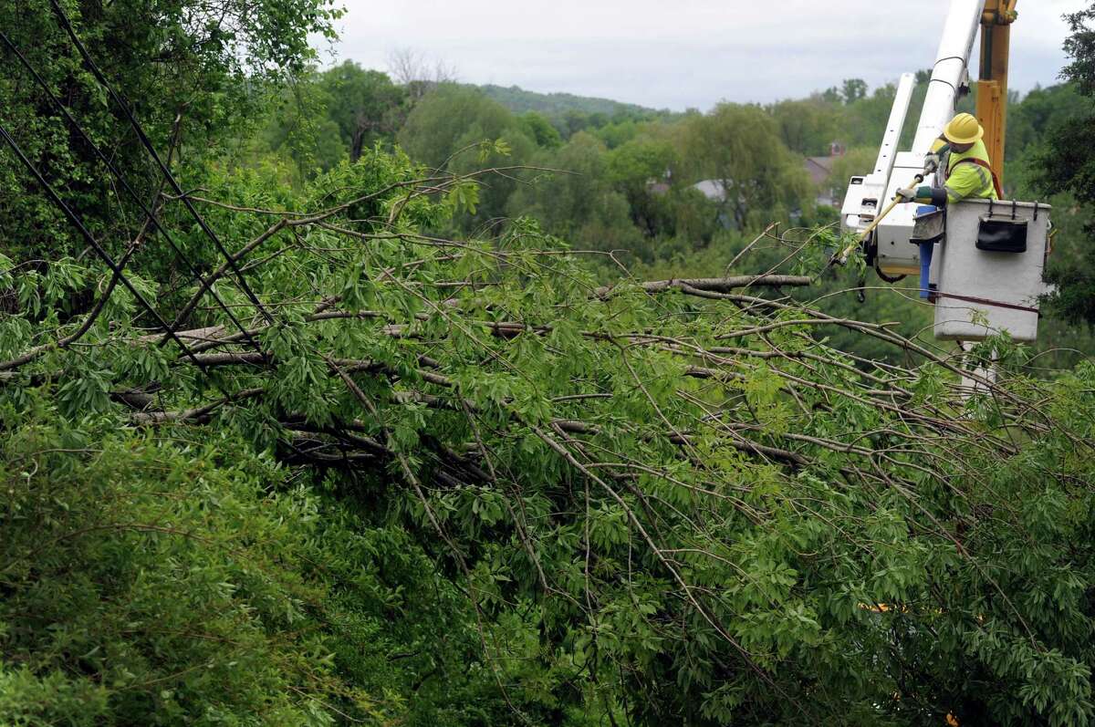 A CL&P worker cuts down branches of a tree that fell over Russeling Ridge Road bringing down wires in New Milford, Conn. during a rain storm Tuesday night, May 27, 2014. Wednesday, May 28, 2014.