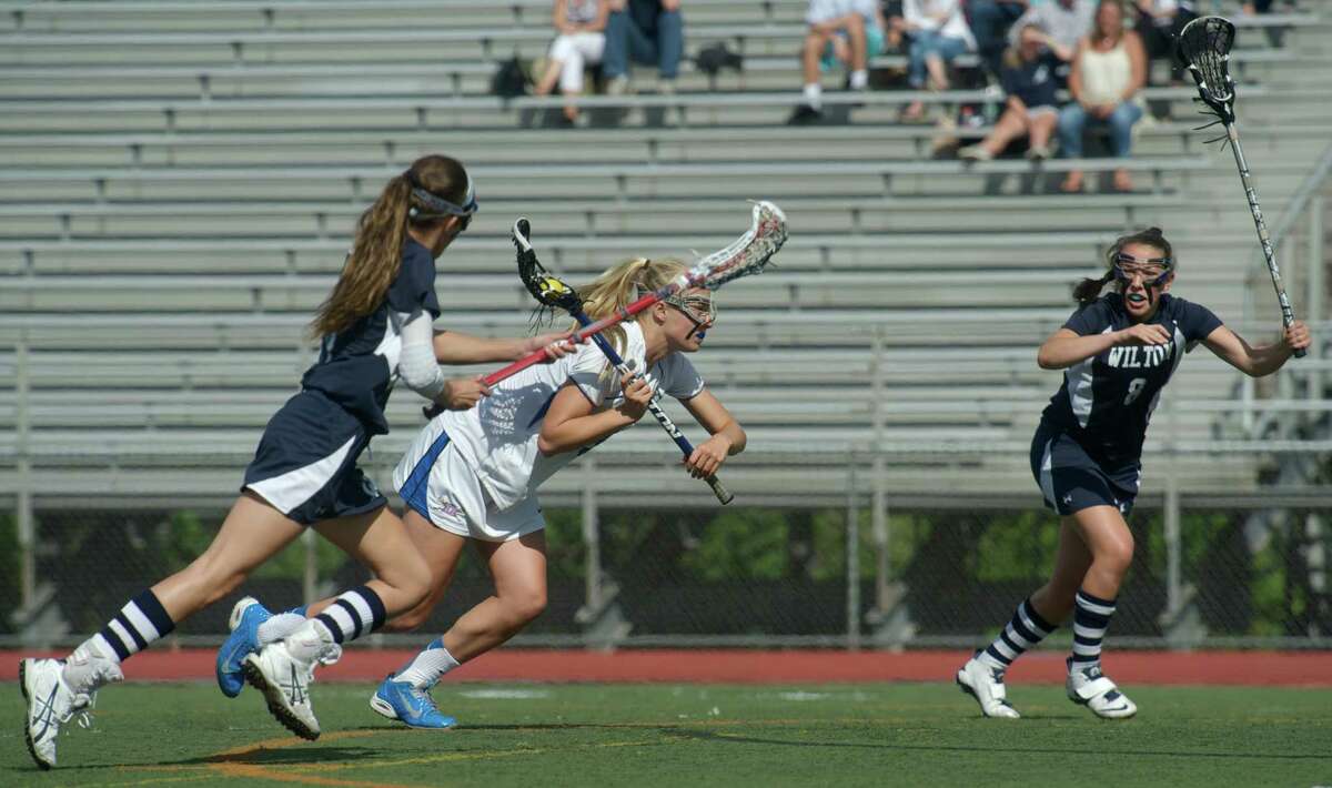 Darien's Hollis Perticone, #29, goes between Wilton's Laine Parsons, #17, and Cecily Freilich, #8, during the FCIAC girls lacrosse championship game between Wilton and Darien high school's, played at Brien McMahon High School, in Norwalk, Conn, on Friday, May 30, 2014. Darien is the FCIAC Girls Lacrosse Champion for 2014, beating Wilton 9-7.