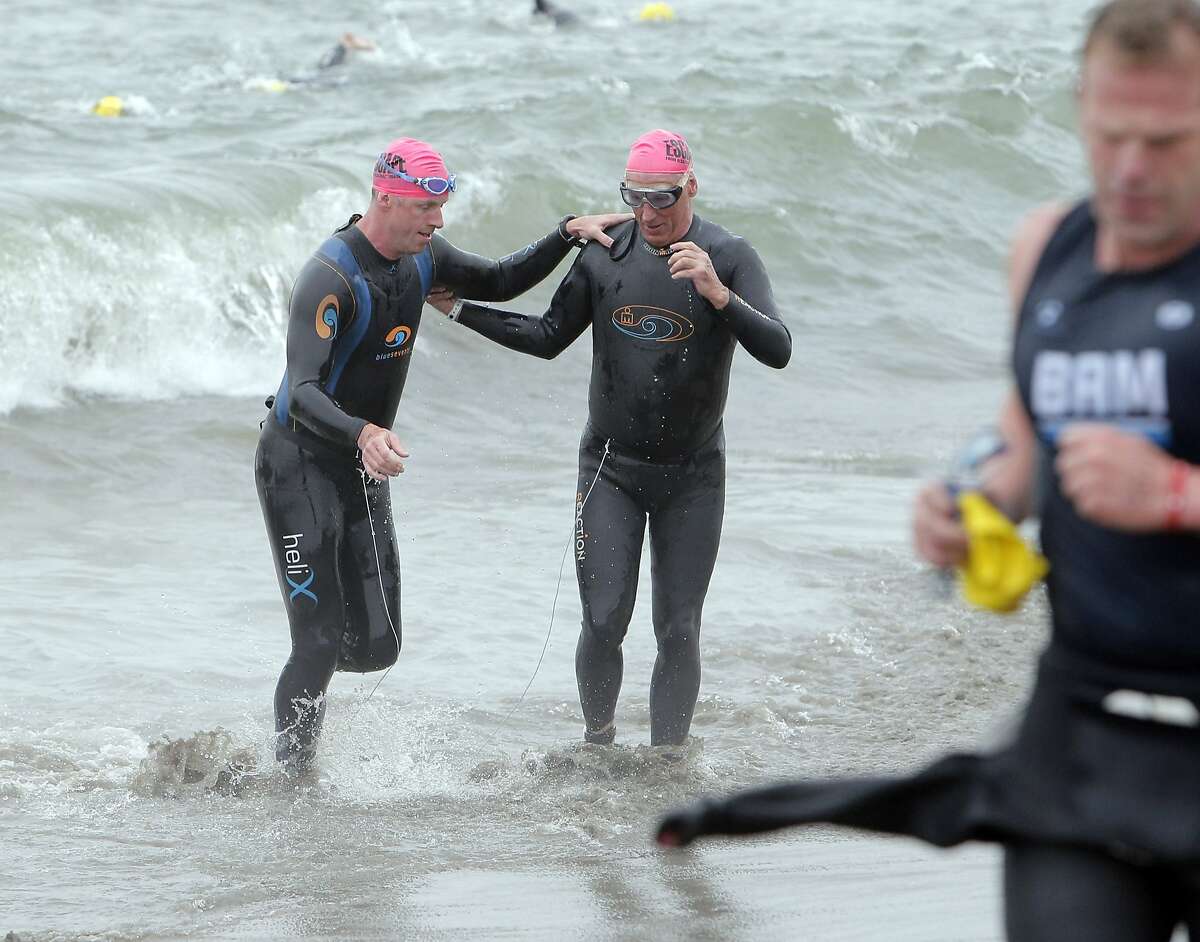 Brian Cowie, who is legally blind, right, and Meyrick Jones, who is a below the knee amputee, left, emerge from the water at Marina Green Beach tethered together during the 34th annual Escape from Alcatraz Triathlon in San Francisco, Calif., on Sunday, June 1, 2014.