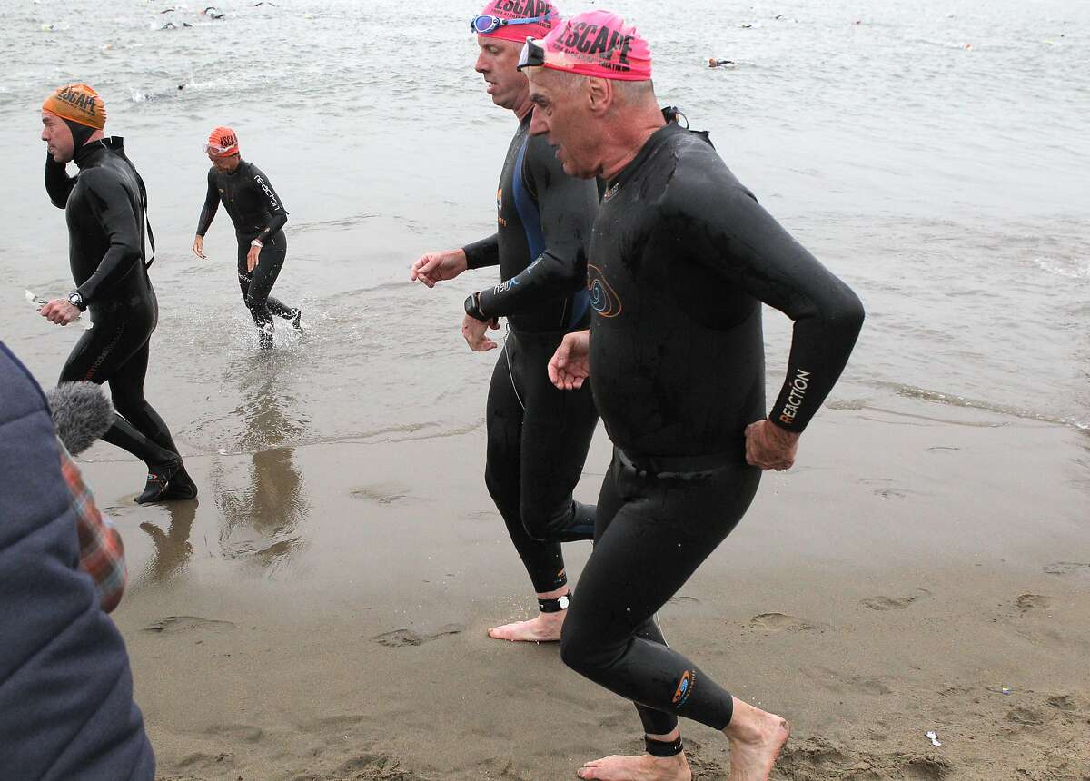 Brian Cowie, who is legally blind, front, and Meyrick Jones, who is a below the knee amputee, rear, emerge from the water at Marina Green Beach tethered together during the 34th annual Escape from Alcatraz Triathlon in San Francisco, Calif., on Sunday, June 1, 2014.
