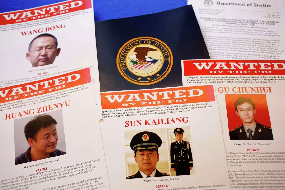 FILE - This May 19, 2014 file photo shows press material displayed at the Justice Department in Washington before a press conference by U.S. Attorney General Eric Holder to announce charges of economic espionage and trade secret theft against five Chinese military officers, all hackers in an international cyber-espionage case. In the two weeks since the Obama administration accused them of hacking into American companies to steal trade secrets, the Chinese officers have yet to be placed on Interpolâs public listing of international fugitives, and there is no evidence that China would even entertain a formal request by the U.S. to extradite them. (AP Photo/Charles Dharapak, File)