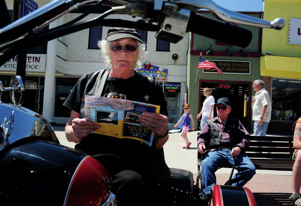 Americade riders, Jeannette Pittsley, 77, from East Freetown, Mass, looks over a brochure for Lake George attractions as her husband, Louis Pittsley, 83, sits on a bench along Canada St. on Monday, June 2, 2014, in Lake George, N.Y. 
