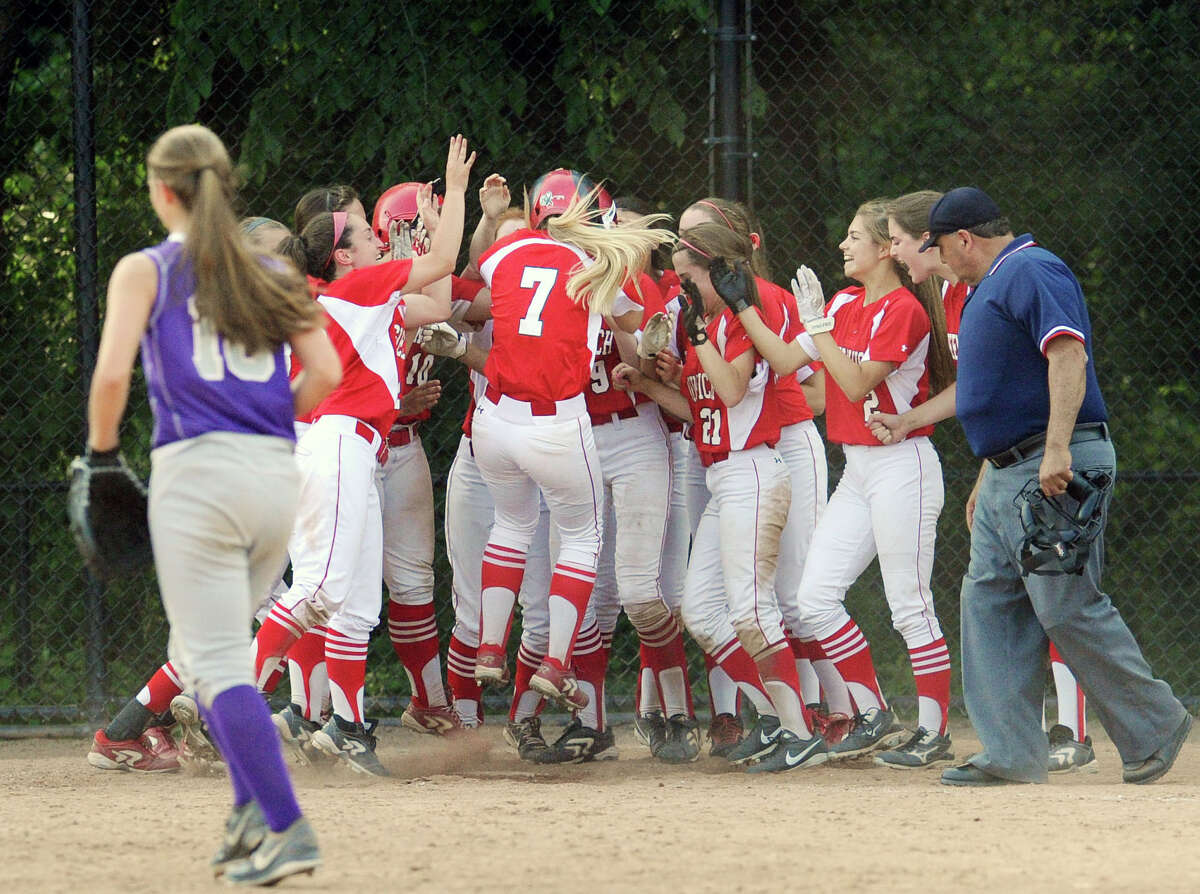 At center, Rebecca DeCarlo (#7) of Greenwich is mobbed by her teammates while touching home plate after DeCarlo hit the walk-off game-winning home run in the bottom of the 8th inning to defeat rival Westhill 3-2 in the Class LL softball game between Greenwich High School and Westhill High School at Greenwich, Tuesday, June 3, 2014.