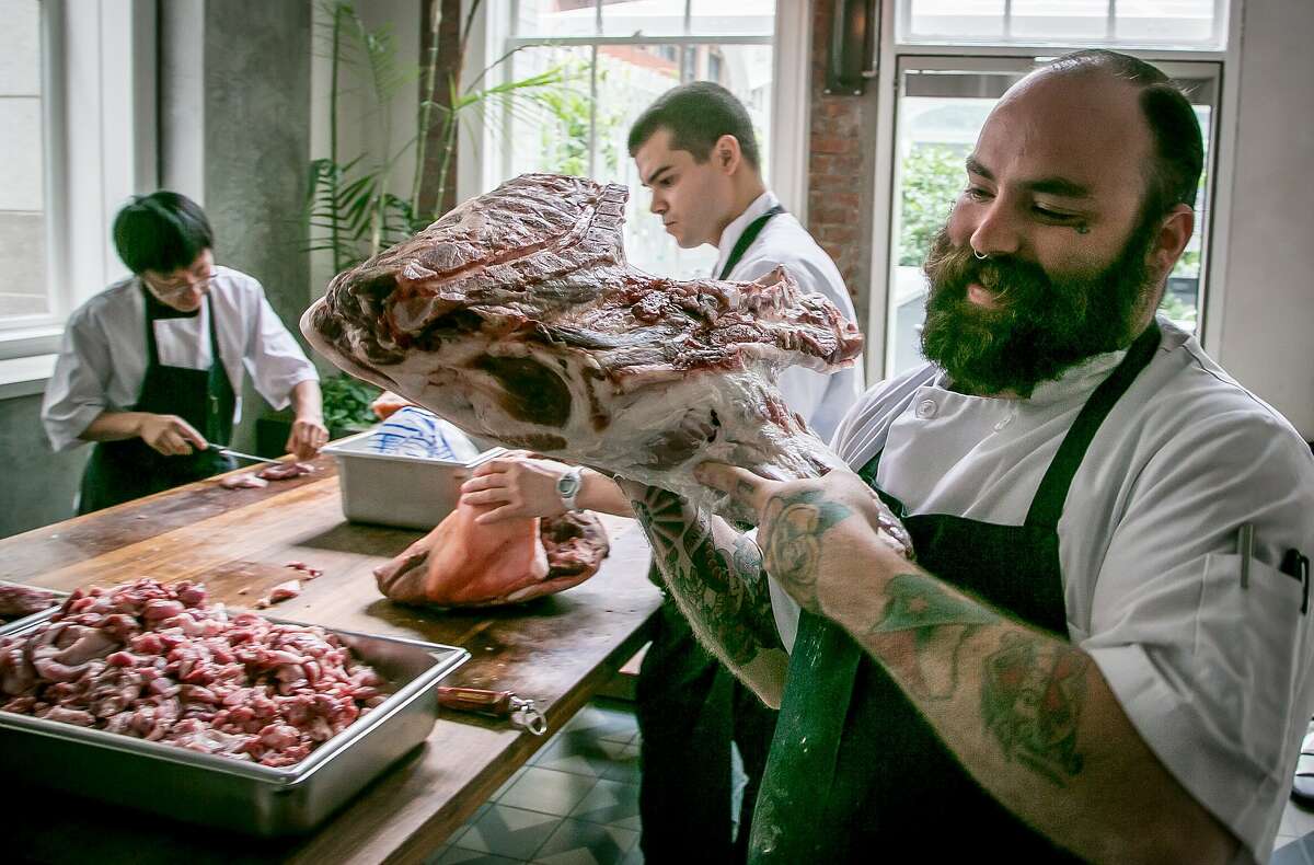 Seth Cone carries a pig leg to the table for butchering at Trou Normand in San Francisco, Calif., is seen on Monday, June 2nd 2014.