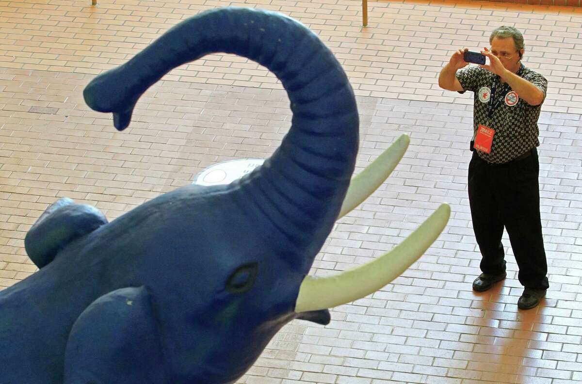 Delegate and registration volunteer Mark Liberto, from Arlington, Texas, pauses to make a photo of the large GOP elephant at the convention center west entrance as people arrive, Wednesday, June 4, 2014, for the Republican Party of Texas state convention (starting Thursday, June 5) at the Fort Worth Convention Center in Fort Worth, Texas. (AP Photo/Star-Telegram, Paul Moseley) MAGAZINES OUT; (FORT WORTH WEEKLY, 360 WEST); INTERNET OUT.