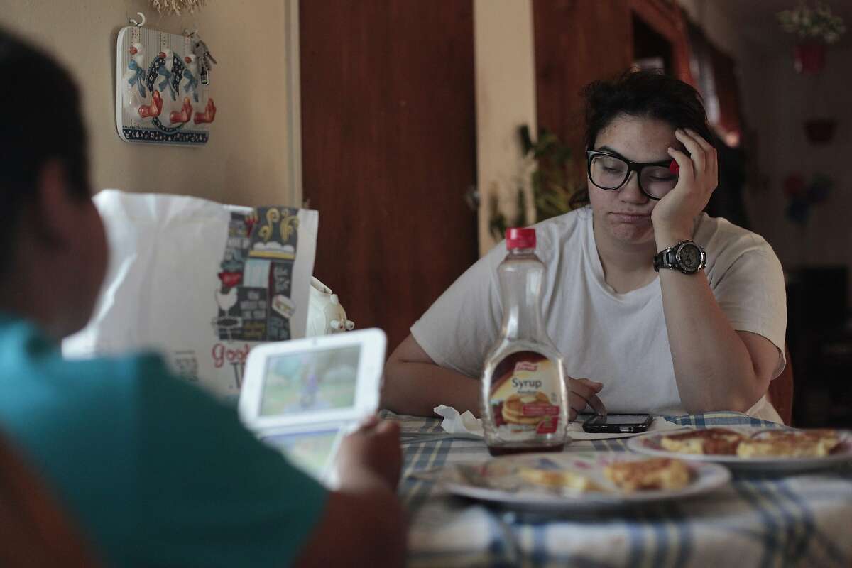 Joanna Lopez rests her eyes as her son Isaac eats his breakfast in Hayward, Calif. on Thursday, June 5, 2014. Lopez has difficulty making ends meet while only making $9.20 an hour at Wal-Mart.