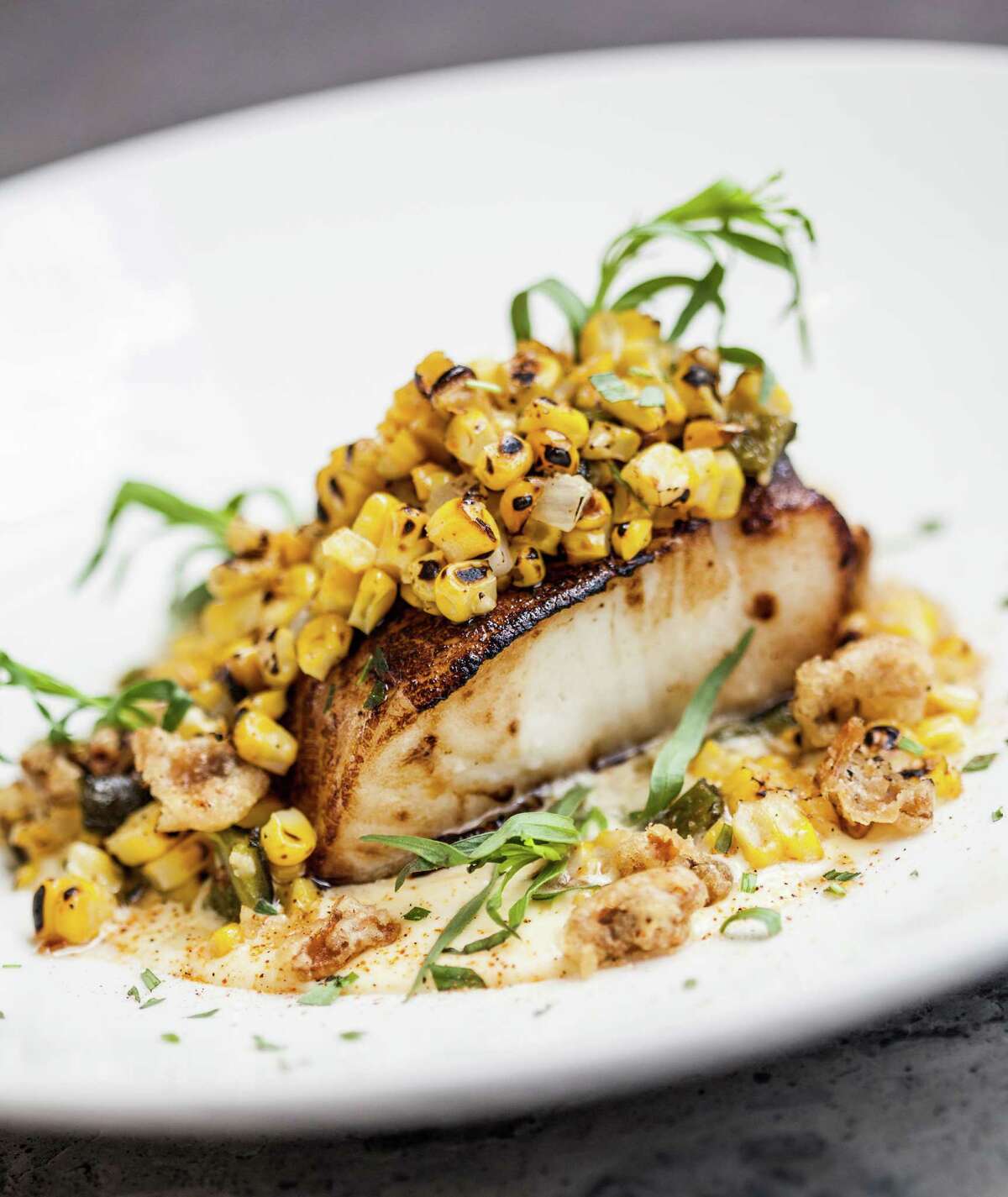 South American sea bass is topped with chargrilled corn, popcorn crema and tempura mushrooms at Américas River Oaks.