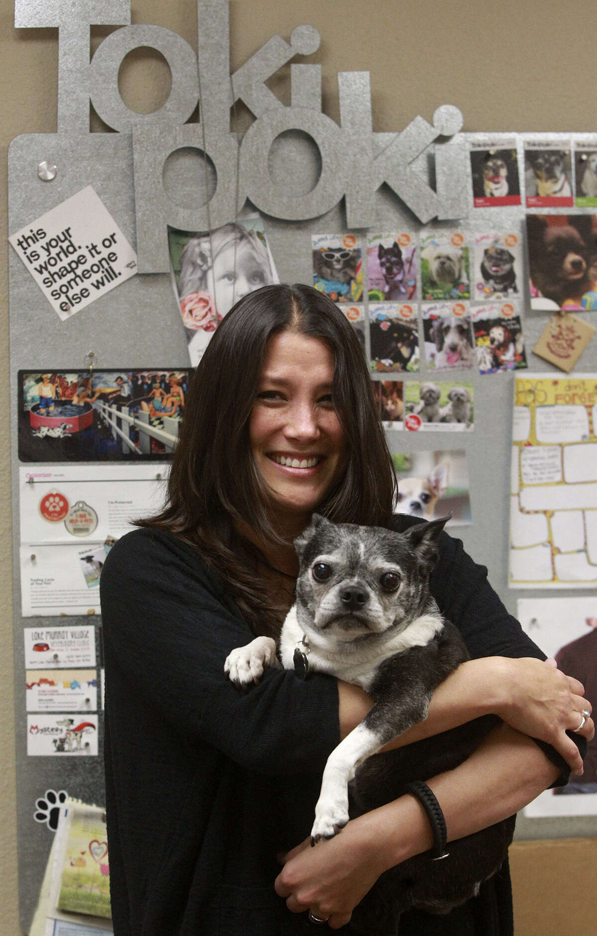 Christy Myhre spends time Tuesday May 13, 2014 with her dog Toki in her office at Toki Poki. Toki Poki makes pet trading cards for pet owners and gives them out to child patients at hospitals. Toki will be 15 years old this year.
