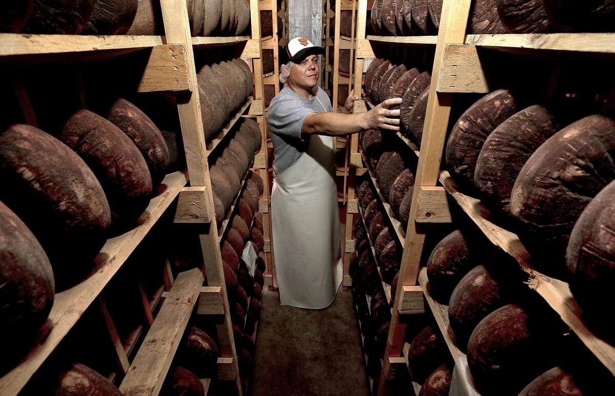 Cheesemaker Gabe Luddy with rounds Dry Monterey Jack cheese being aged on wooden racks at the Vella Cheese Co. in Sonoma, Calif. as seen on Tuesday June 10, 2014.
