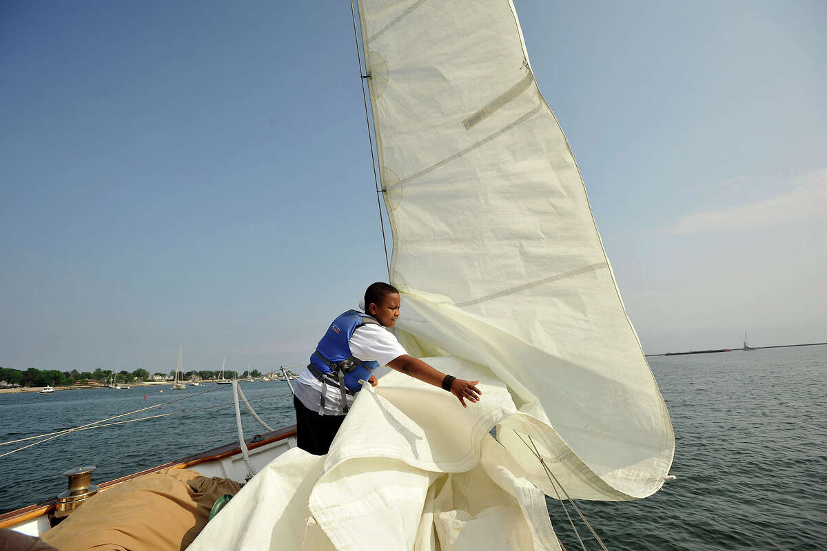 Gregory Perard helps bring in a sail during a sailboat ride on the Ticonderoga on the Long Island Sound as part of the graduation festivities associated with the Young Mariners' 10th annual graduation ceremony which was held at the Stamford Yacht Club in Stamford, Conn., on Tuesday, June 10, 2014. The Young Mariners Afterschool Enrichment Program is a STEM-based program that helps underserved and at-risk students through the universal principles of sailing.