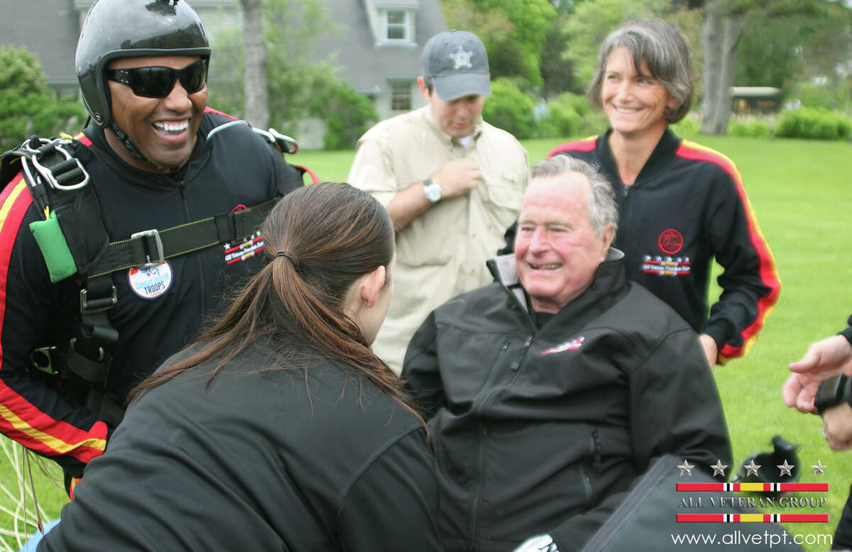 In this photo provided by the All Veteran Parachute Team, former President George H.W. Bush is checked by a doctor with the All Veteran Parachute Team after his landing of a parachute jump on his 90th birthday in Kennebunkport, Maine, Thursday, June 12, 2014. (AP Photo/All Veteran Parachute Team, Kenneth Wasley)