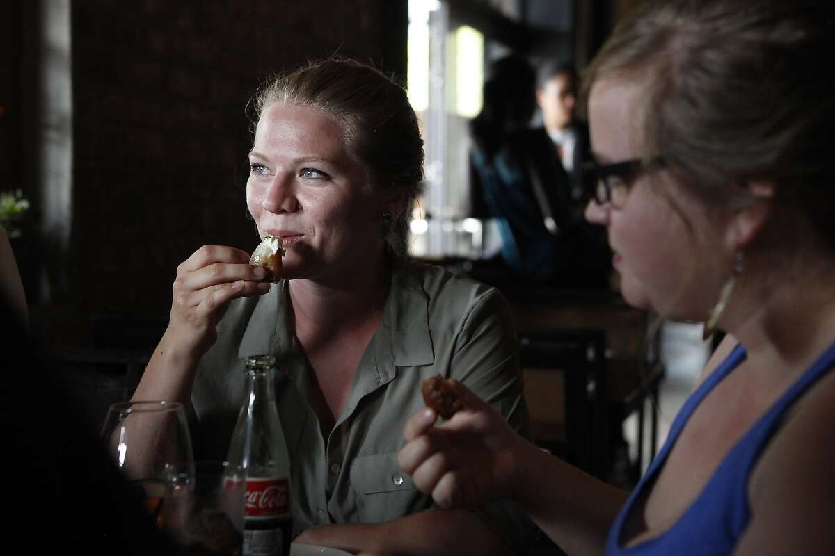Allie Sieben, left, eats the fried fennel and onion petals appetizer with her sister Taylor Sieben at the Dock restaurant in Oakland, CA, Tuesday June 10, 2014.