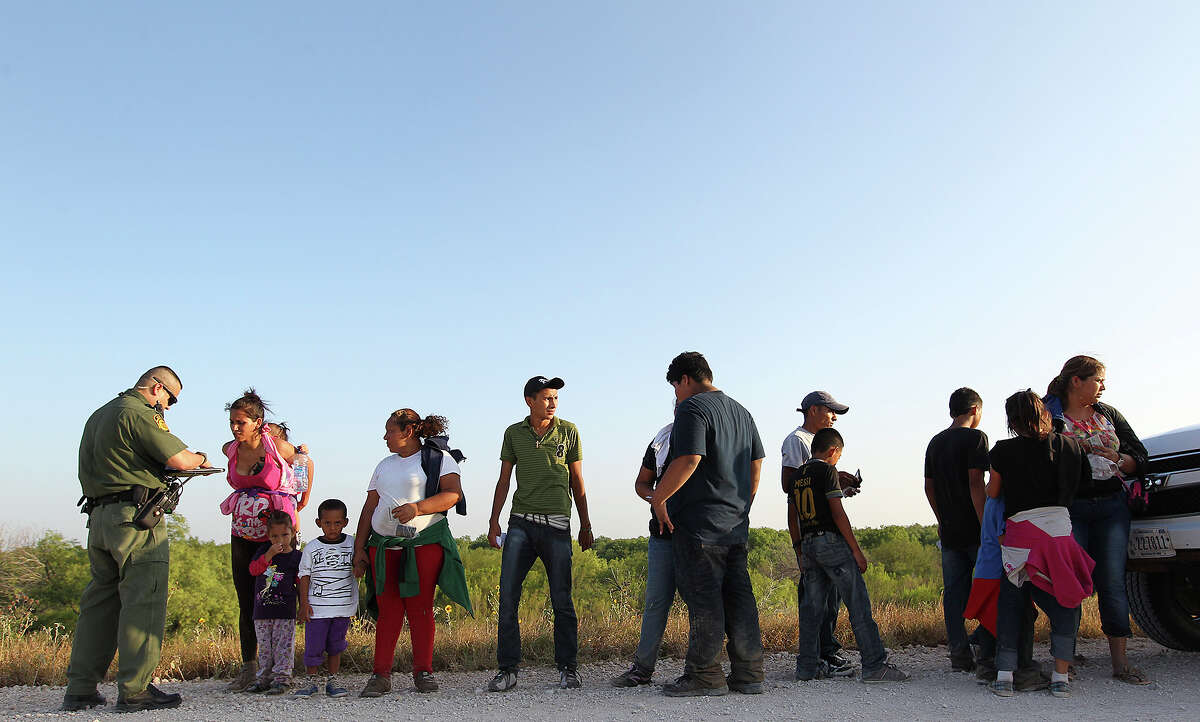 U.S. Border Patrol agents question a group of adult and minor immigrants who walked up to them near Anzalduas Park, southwest of McAllen, Texas, Wednesday, June 11, 2014. To avoid media attention, agents on the scene hustled the immigrants into a nearby transportation van. A wave of Central American adults with children and unaccompanied minors has overwhelmed U.S. Immigration and Customs detention centers. Immigration officials release some of them on their own recognizance after undergoing processing.