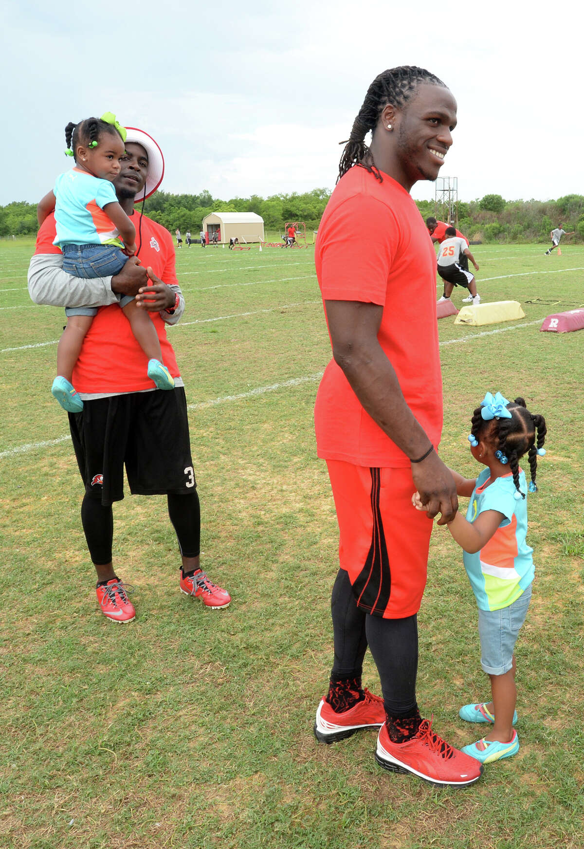 Danny Gorrer, left, holds Makenzie Charles, 2, while Jamaal Charles, 2, holds hands with Makaila Charles, 3, during the famed football player's sports camp at Memorial High School on Friday. Photo taken Friday, June 13, 2014 Guiseppe Barranco/@spotnewsshooter