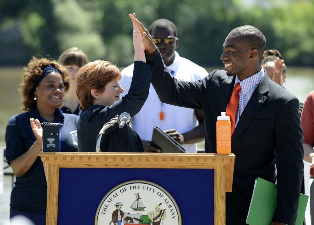 Albany Mayor Kathy Sheehan, left, and recreation commissioner Jonathan Jones, right, give a celebratory high five after blowing whistles to start a 67-day fitness initiative called the 1609 Fitness Challenge Monday morning, June 16, 2014, at Jennings Landing in Albany, N.Y. The challenge is designed to encourage Albany residents to partake in 30 minutes of daily exercise from June 16 through Aug. 22. Points are awarded for exercise, with prizes offered to the most active participants. (Will Waldron/Times Union)