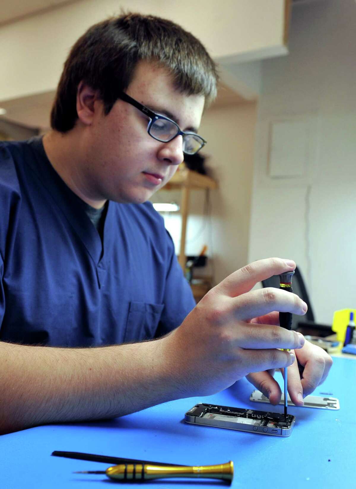Aron Kowalski, 18, of New Milford, Conn. disassembles an iPhone at the Phone Surgeon on Federal Road in Danbury, Conn. Monday, June 16, 2014.