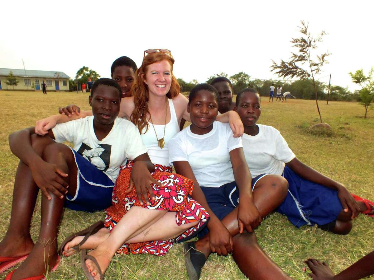 Elizabeth Moran, a New Canaan woman who works with Nairobi-based organization WISER, Women's Institute for Secondary Education and Research, relaxes with a group of students outside a school in Kenya in February 2014.