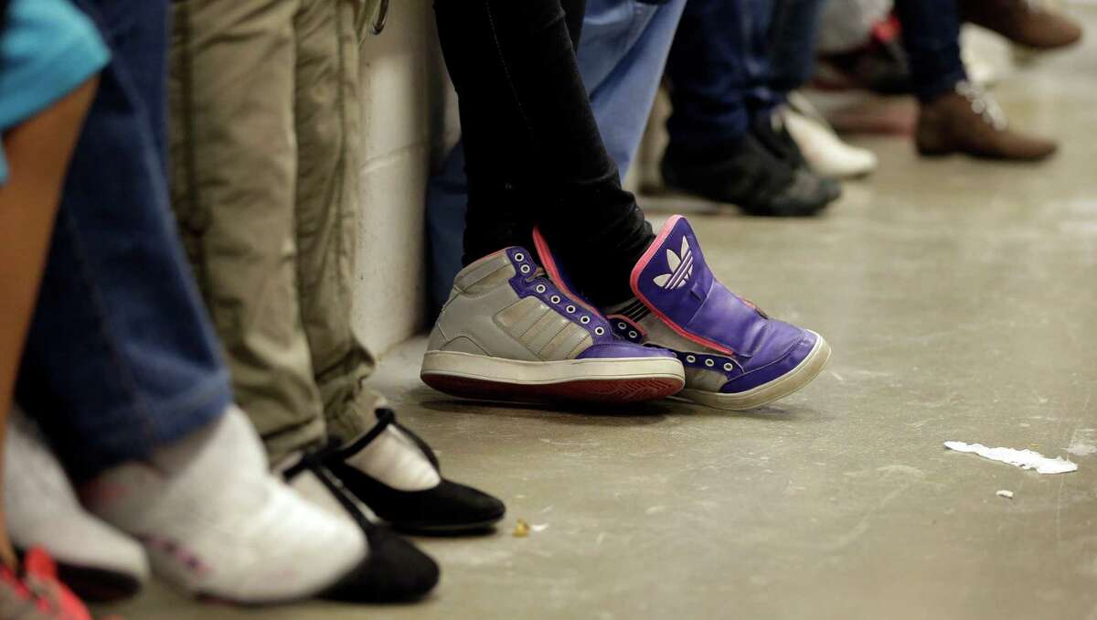 Detainees, with the shoe strings removed, wait at a U.S. Customs and Border Protection processing facility, Wednesday, June 18, 2014, in Brownsville,Texas. CPB provided media tours Wednesday of two locations in Brownsville and Nogales, Ariz. that have been central to processing the more than 47,000 unaccompanied children who have entered the country illegally since Oct. 1.