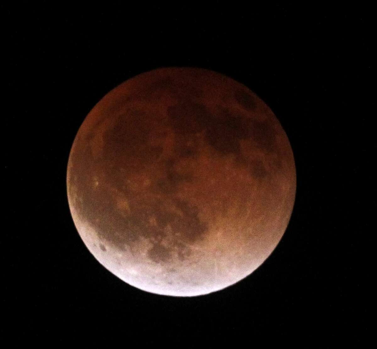 The moon completely crosses the earth's shadow in a total lunar eclipse, becoming a "blood moon" because of sunlight bending through Earth's atmosphere and hitting the moon.