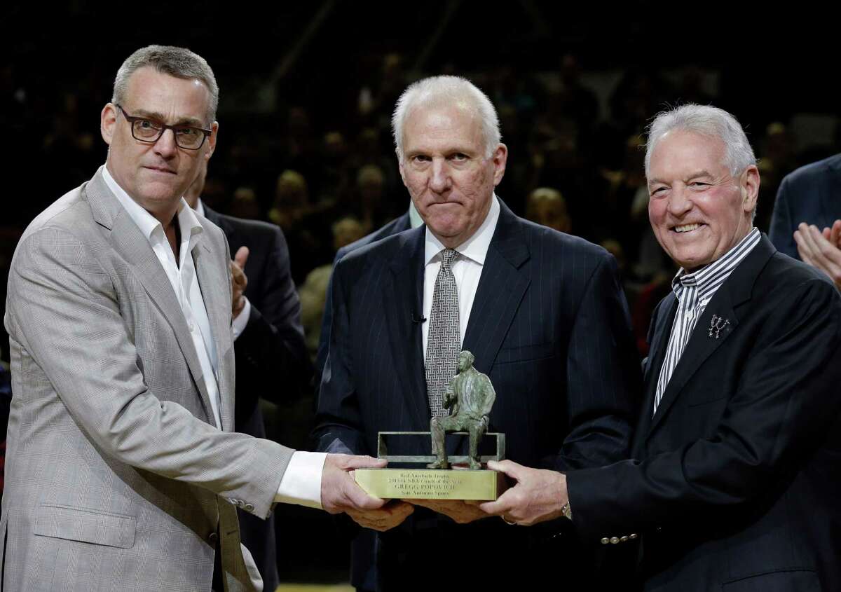 In this Wednesday, April 23, 2014 photo, San Antonio Spurs coach Gregg Popovich, center, stands with general manager R.C.Buford, left, and team owner Peter Holt, as he holds his NBA coach of the year trophy during the first half of Game 2 of the opening-round NBA basketball playoff series, in San Antonio. Buford has been named NBA Executive of the Year. (AP Photo/Eric Gay, File)