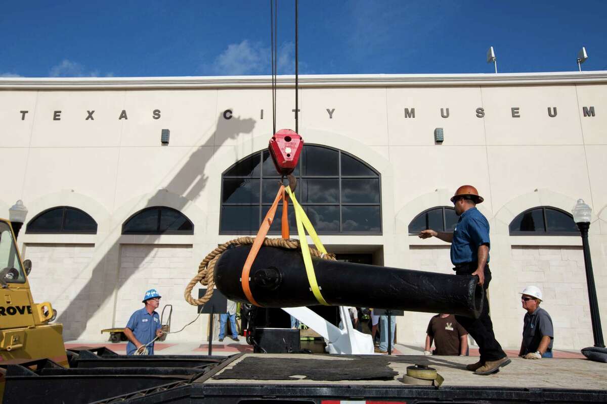Rene Delbosque keeps one hand on the barrel Wednesday as a 12-foot Civil War cannon is delivered to the Texas City Museum.