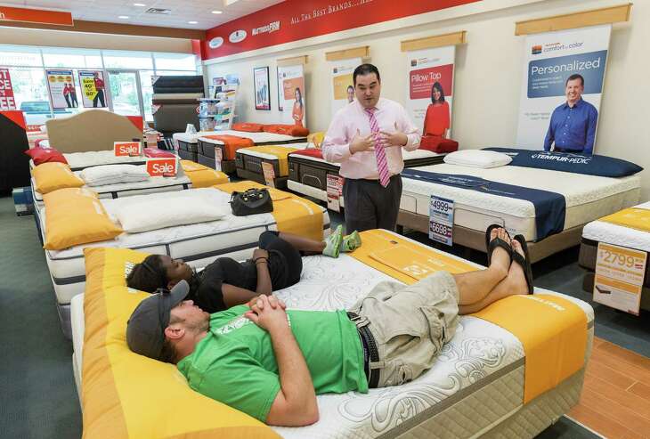 Mattress Firm at 2071 Westheimer, Ste C.  Assistant Store Manager Alejandro Guerra (in pink long sleeve shirt) discusses bed options with Andy Hollister (green shirt, shorts) and Maxina Kroma (black shirt, shorts).
(Craig H. Hartley/For the Chronicle)