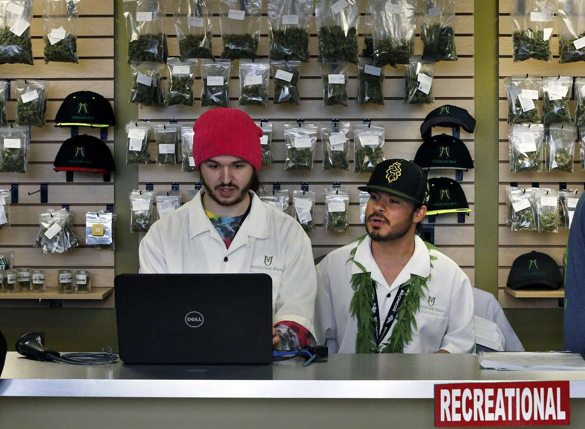 In this Jan. 1, 2014, file photo, employees Chris Broussard, left, and David Marlow, work behind sales counter inside Medicine Man marijuana retail store, which opened as a legal recreational retail outlet in Denver. Colorado made roughly $2 million in marijuana taxes in January, state revenue officials reported Monday, March 10, 2014, in the world's first accounting of the recreational pot business. (AP Photo/Brennan Linsley, File)
