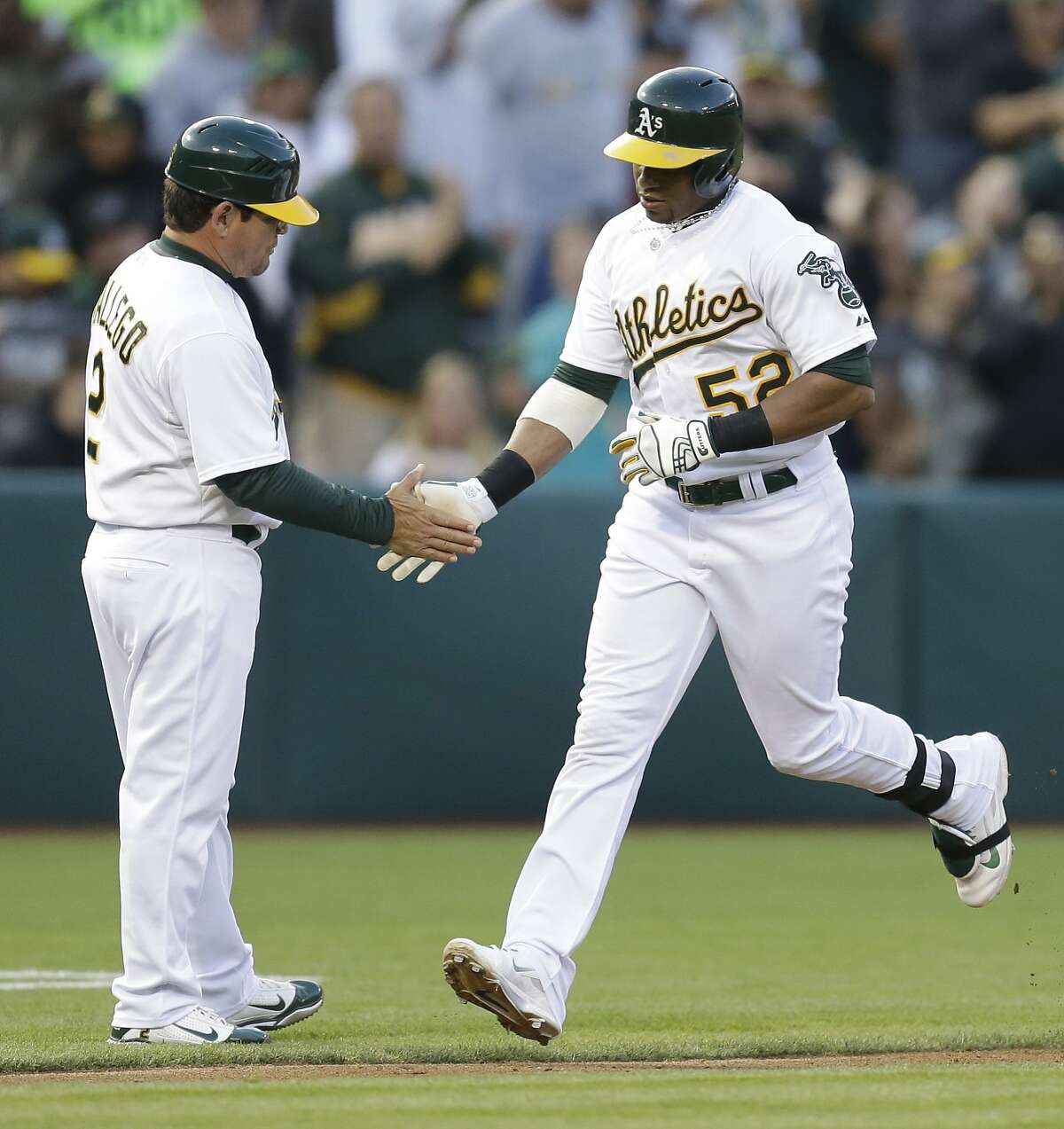 Oakland Athletics' Yoenis Cespedes, right, is congratulated by third base coach Mike Gallego after hitting a home run off Boston Red Sox pitcher Jake Peavy in the third inning of a baseball game Thursday, June 19, 2014, in Oakland, Calif. (AP Photo/Ben Margot)