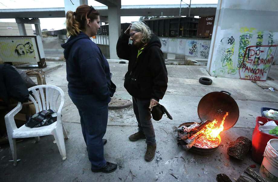 Asten Jones, left, checks on her mother, Sandy Snell at her camp along I 10 near Culebra, as a train passes by. Photo: BOB OWEN, San Antonio Express-News / © 2012 San Antonio Express-News