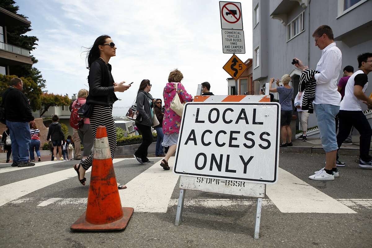 Tourists are seen walking past signs at the top of Lombard St. after it was closed off to cars as part of a pilot program by the MTA testing weekend closures of the popular tourist destination, in San Francisco, CA, Saturday June 21, 2014.