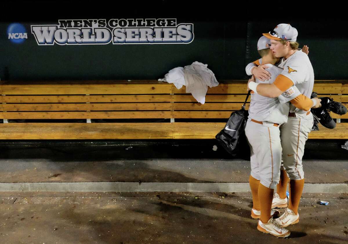Texas' Mark Payton, left, and Kacy Clemens, right, hug in the dugout after Texas lost 4-3 to Vanderbilt in 10 innings in an NCAA baseball College World Series elimination game in Omaha, Neb., Saturday, June 21, 2014. Vanderbilt advanced to the championship series. (AP Photo/Eric Francis)