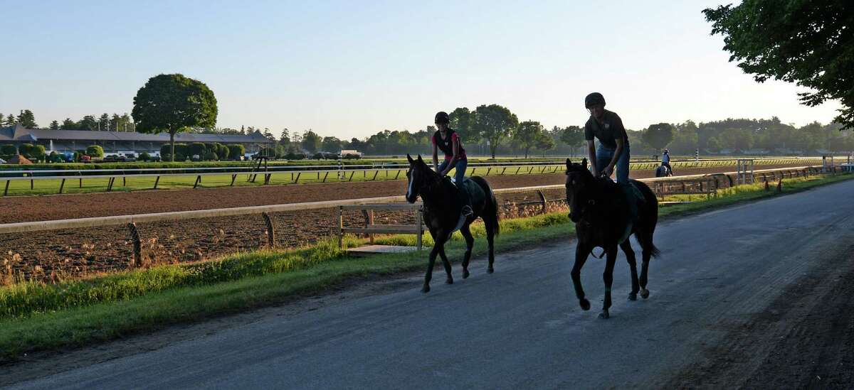 Trainer Arch Kingsley aboard Central Banker, right, and Grace LaBarre aboard Southbound Swinger, left, jog down the lane at Saratoga Race Course on the opening day of the main track for training Monday morning, June 23, 2014, in Saratoga Springs, N.Y. The 151st race meeting at the historic track will begin on July 18th and run through Labor Day. (Skip Dickstein/Times Union)