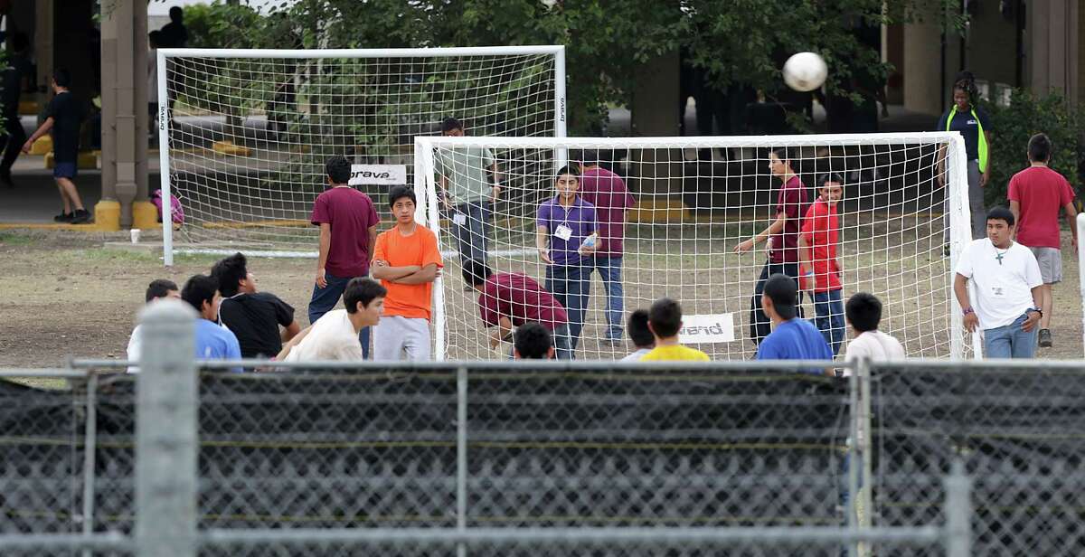 Young male immigrants play soccer behind a screened off fence at the old housing facilities at Lackland Air Force Base. Texas Attorney General Greg Abbott and U.S. Senator Ted Cruz addressed members of the media following their tour of the facilities housing young immigrants at Lackland Air Force Base in San Anotnio, TX, Monday, June 23, 2014. U.S. Rep. Michael Burgess also went on the tour.