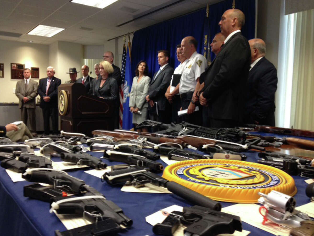 Dora B. Schriro, commissioner of the Connecticut Department of Emergency Services and Public Protection (at the podium) and several federal, state and local law enforcement personnel surround a table loaded with seized guns during a four-month long initiative in Bridgeport and New Haven.