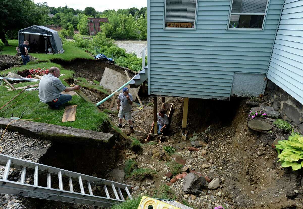 Workers repair damage flood damge to a home Thursday morning, June 26, 2014, at 35 North Street in Valley Falls, N.Y. Heavy rains from Wednesday's fast moving storm caused damage throughout the region. (Skip Dickstein / Times Union)