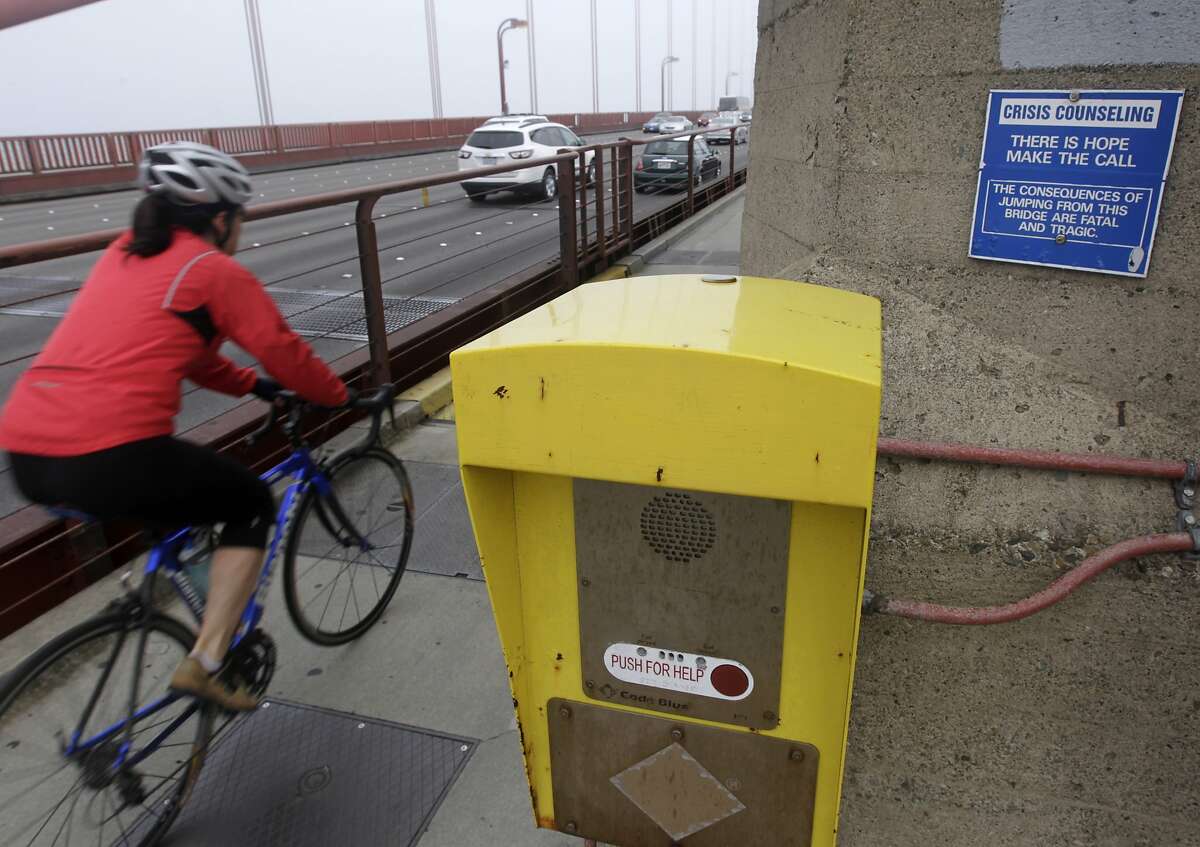 A bicyclist rides across the Golden Gate Bridge past an emergency call box to suicide prevention counselors before transit district board of directors voted unanimously in favor of erecting a suicide barrier on the iconic bridge in San Francisco, Calif. on Friday, June 27, 2014.