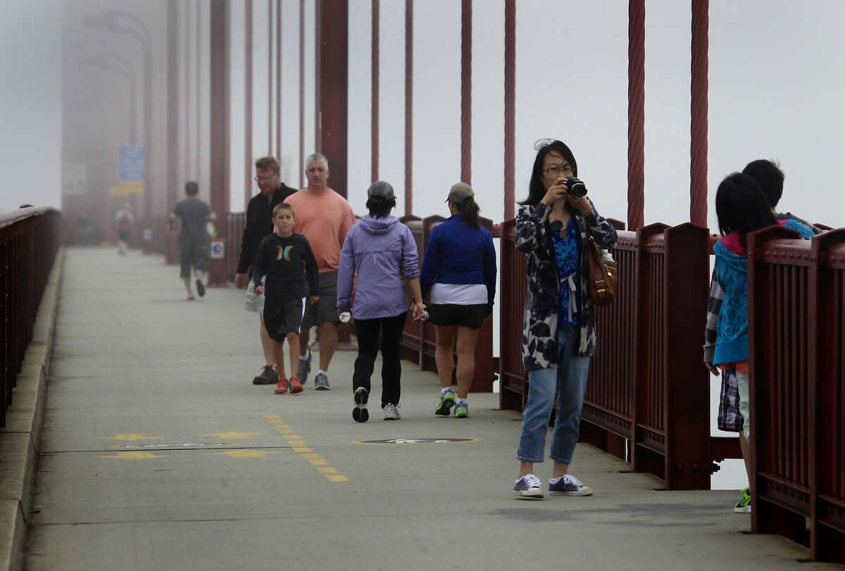 Sightseers stroll across the Golden Gate Bridge before the transit district board of directors vote unanimously in favor of erecting a suicide barrier on the iconic bridge in San Francisco, Calif. on Friday, June 27, 2014.
