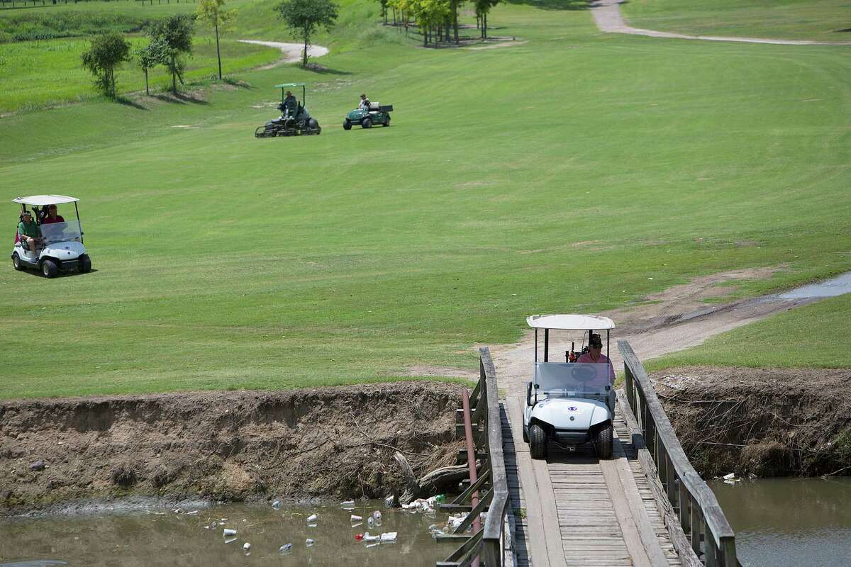Golfers ride to the green over a waterway full of garbage on the seventh hole at Gus Wortham ﻿Golf Course ﻿on Tuesday﻿.﻿