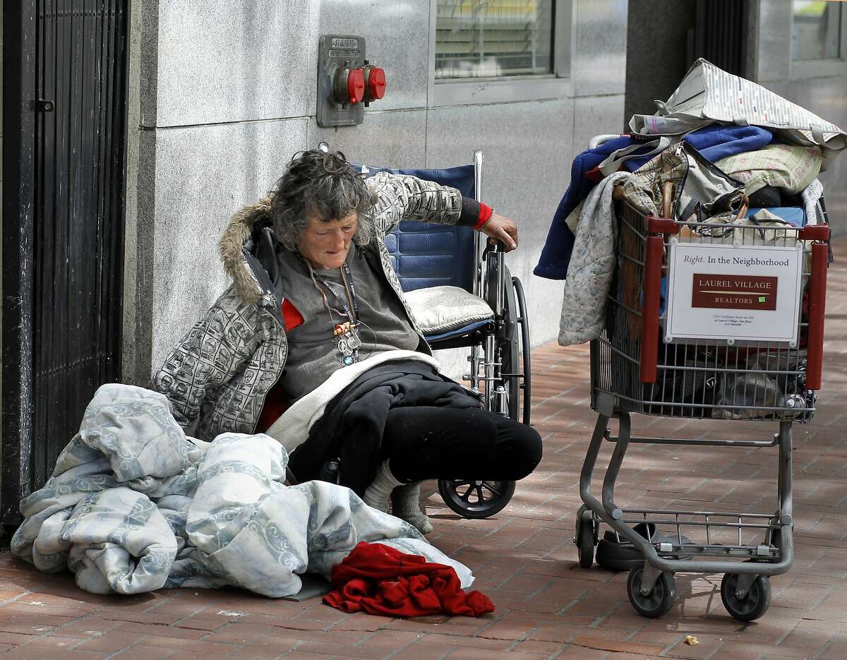 Robin Wilden, a longtime homeless woman, struggles to return to her wheelchair after waking on Market Street. It has been ten years since the original Care Not Cash program was adopted in San Francisco, Calif. Although thousands have been housed, the streets are still full of homeless people.