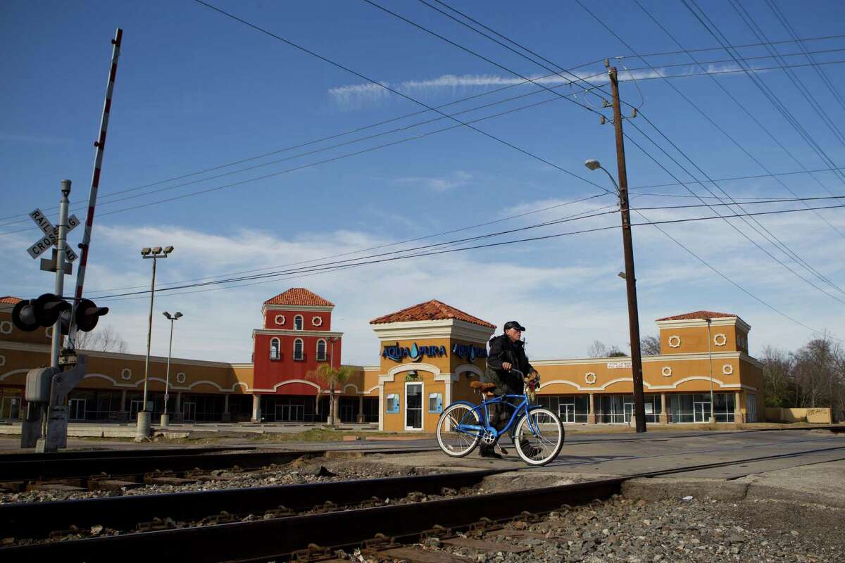 A cyclist walks his bicycle across the railroad tracks on Harrisburg near Hughes on Feb. 5. Metro was planning an underpass of the tracks, but since it discovered more contamination than expected in the area, it can't disturb the ground. Now it wants to build an overpass instead.